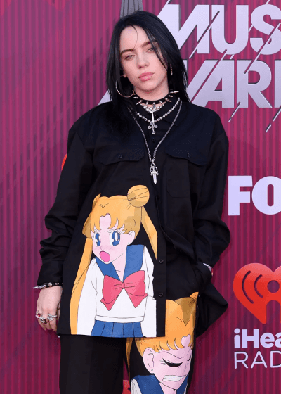 Billie Elish posing in front of music awards.