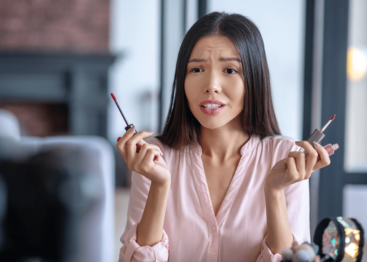 Beauty blogger choosing between lip gloss or lip oil