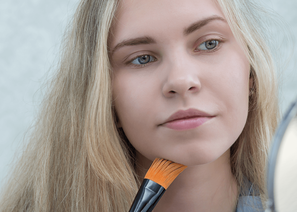 Girl using foundation brush on chin