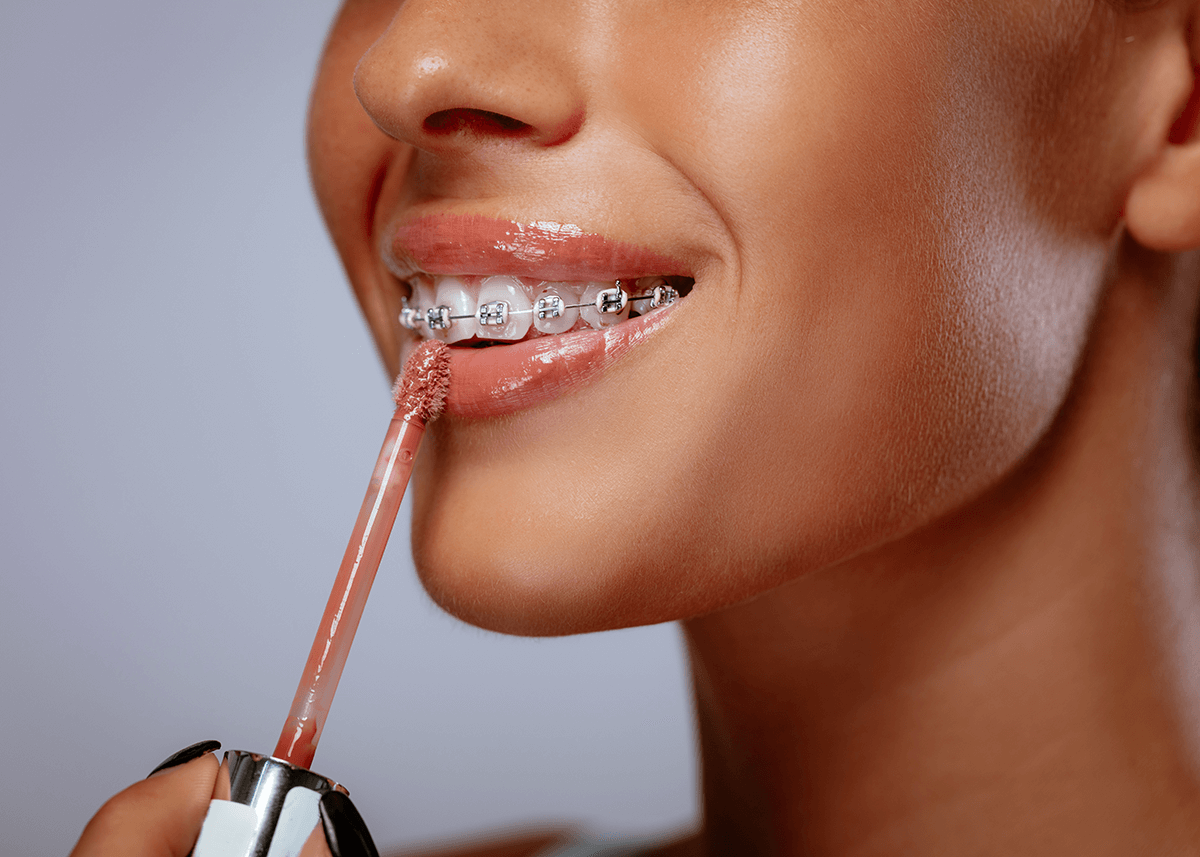 Woman with braces applying Lip Gloss