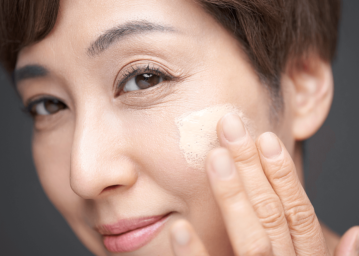Woman applying foundation to cheek with fingers