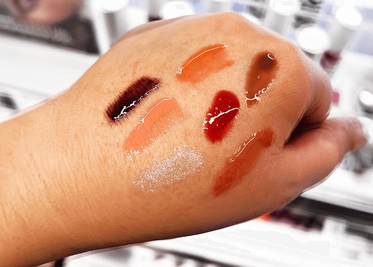 Back of hand applying lip oil swatches