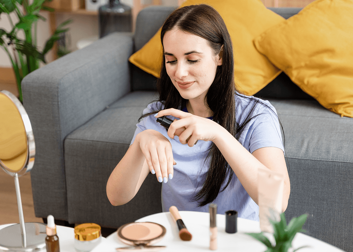 Girl behind table applying foundation to back of hand